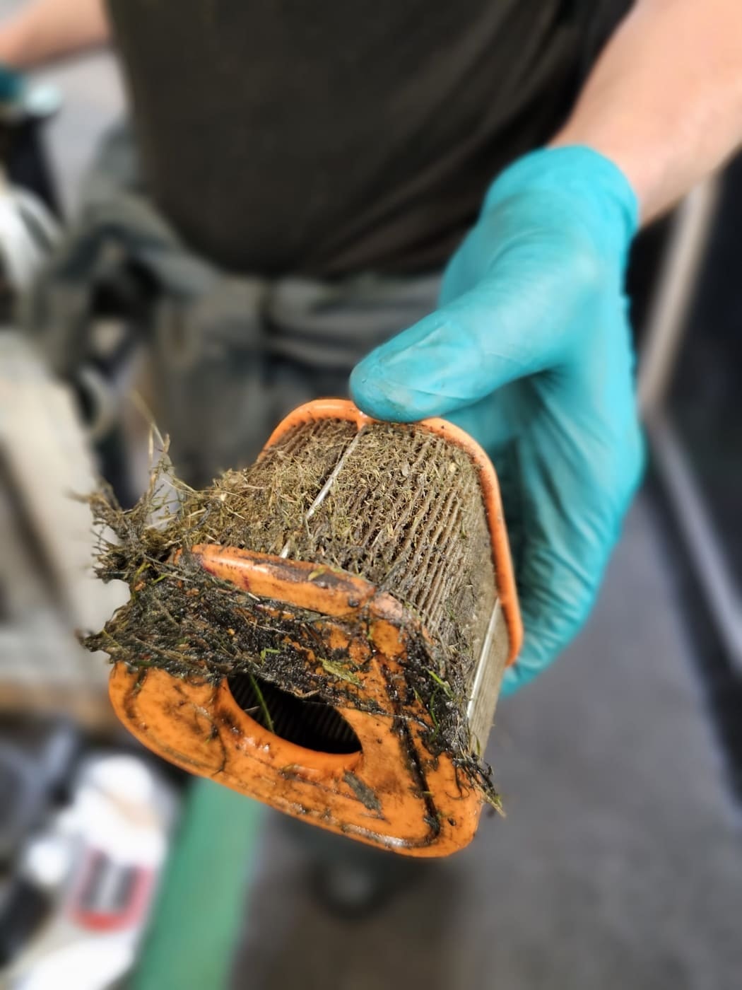 An air filter clogged with grass and oily dirt