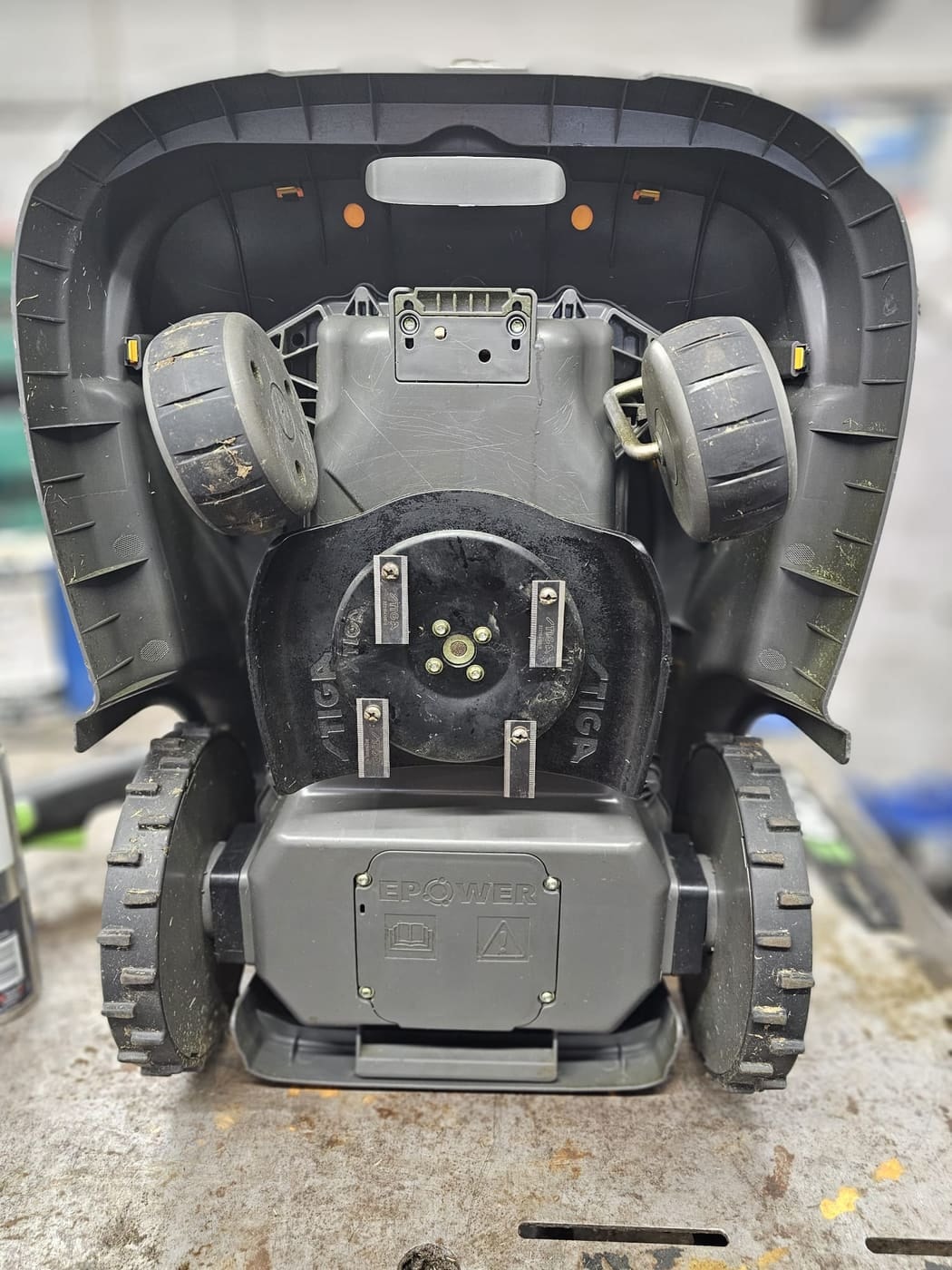 The underside of a Stiga robot mower showing the blade disc and wheels