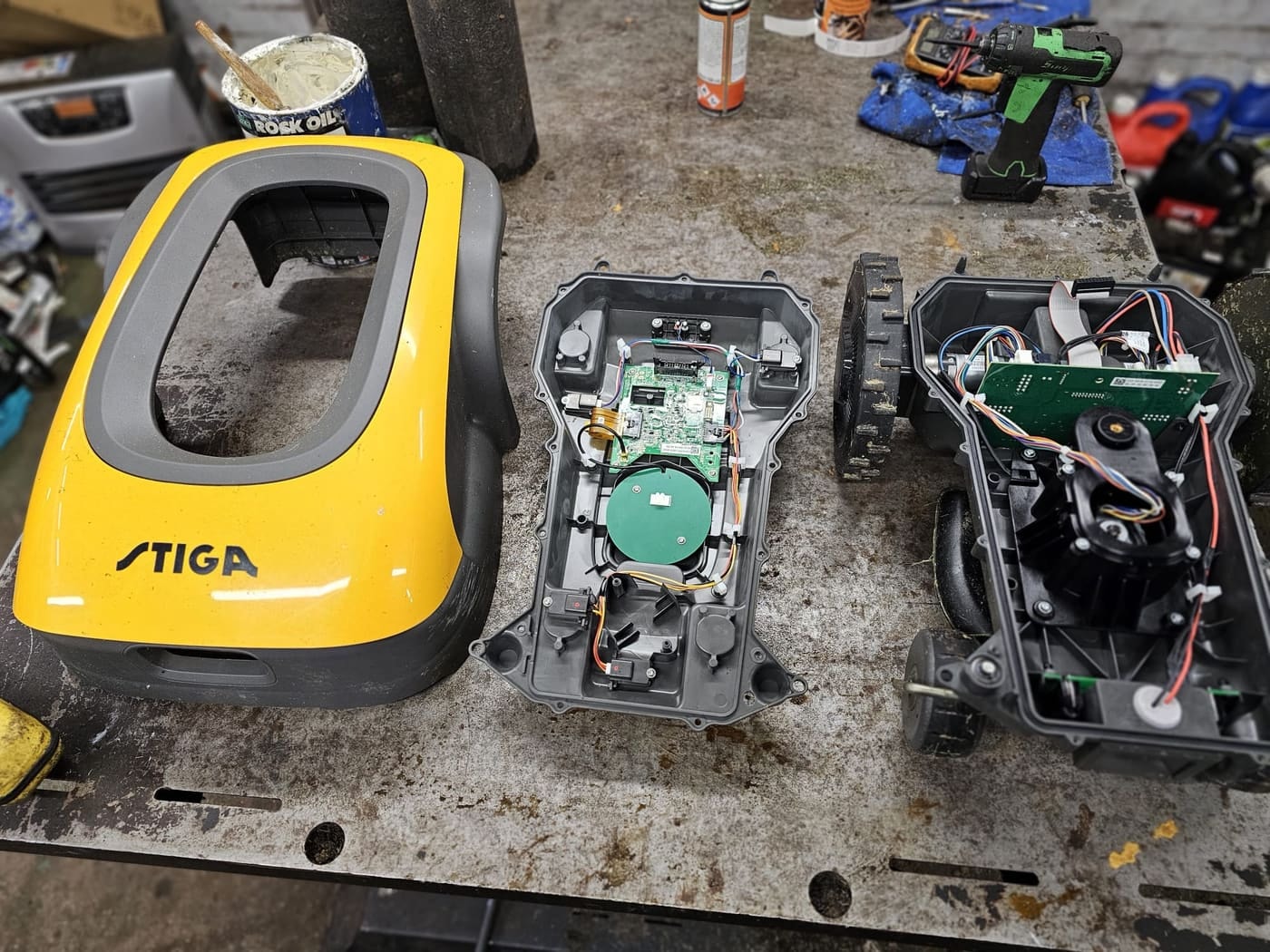 A Stiga robot mower's shell, chassis and electronics laid out on the bench