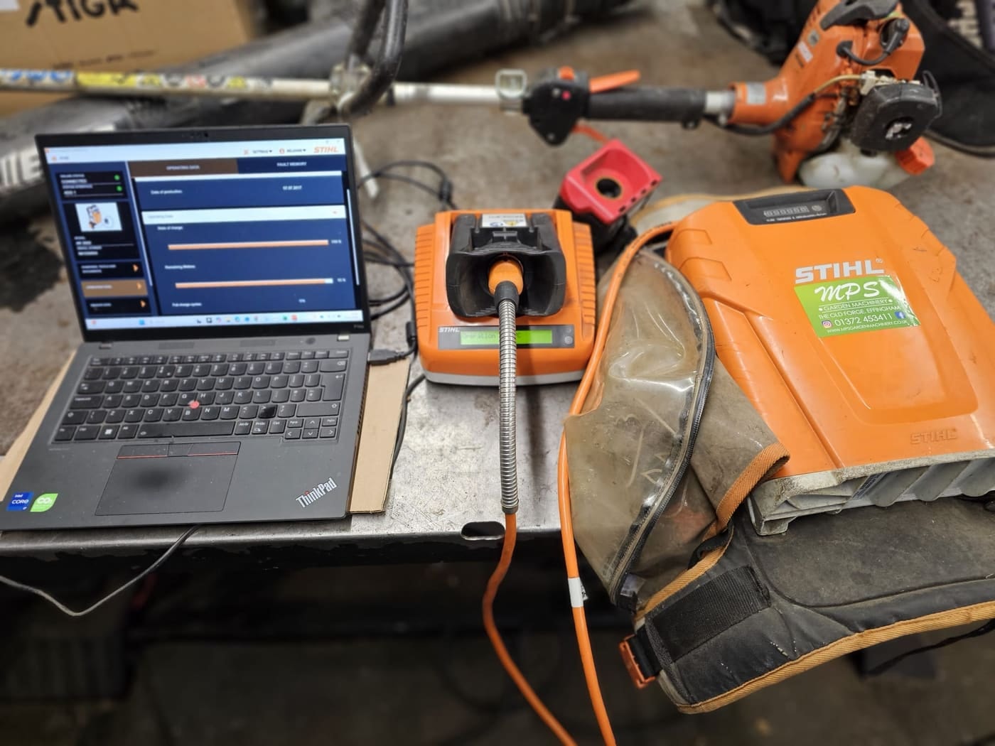 A STIHL backpack battery connected to STIHL diagnostic software on a laptop